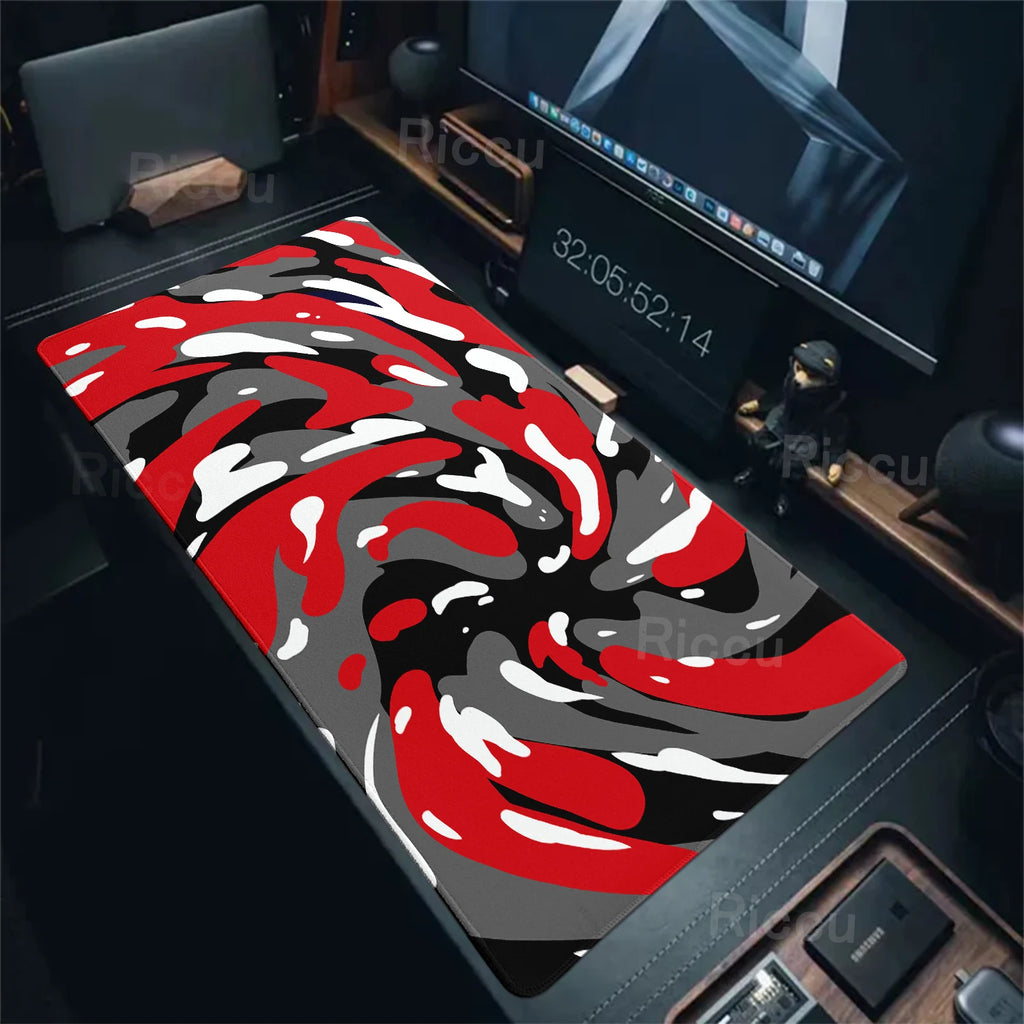 Red, black, and white camouflage mouse pad on a desk with computer equipment.