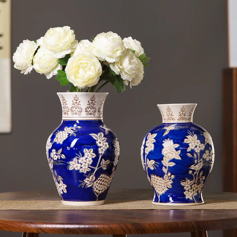 Two blue vases with white floral patterns on a wooden table against a gray wall.