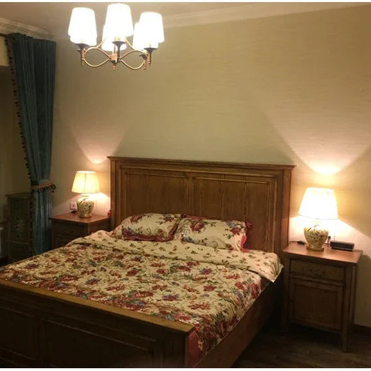 Bedroom with floral bedspread, wooden headboard, and lamps on nightstands.