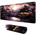 Wide desk mat with dark cherry blossom night scene, glowing Japanese house reflected in a moonlit river