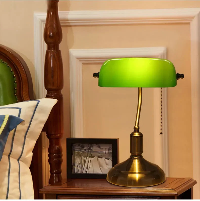 Green glass banker-style desktop lamp with antique brass metal base and pull-chain detail