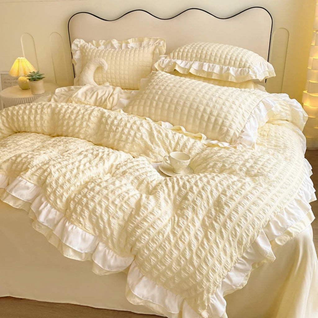 Cream-colored ruffled duvet cover set on a bed with pillows.