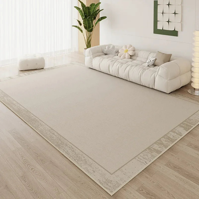 Large cream area rug with subtle vintage-wash border in a bright minimalist living room with white cloud sofa