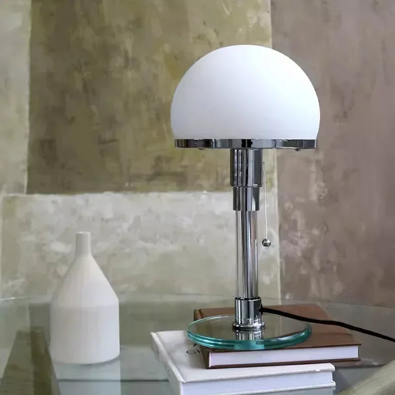 Table lamp with a white glass shade on a reflective surface with a neutral background