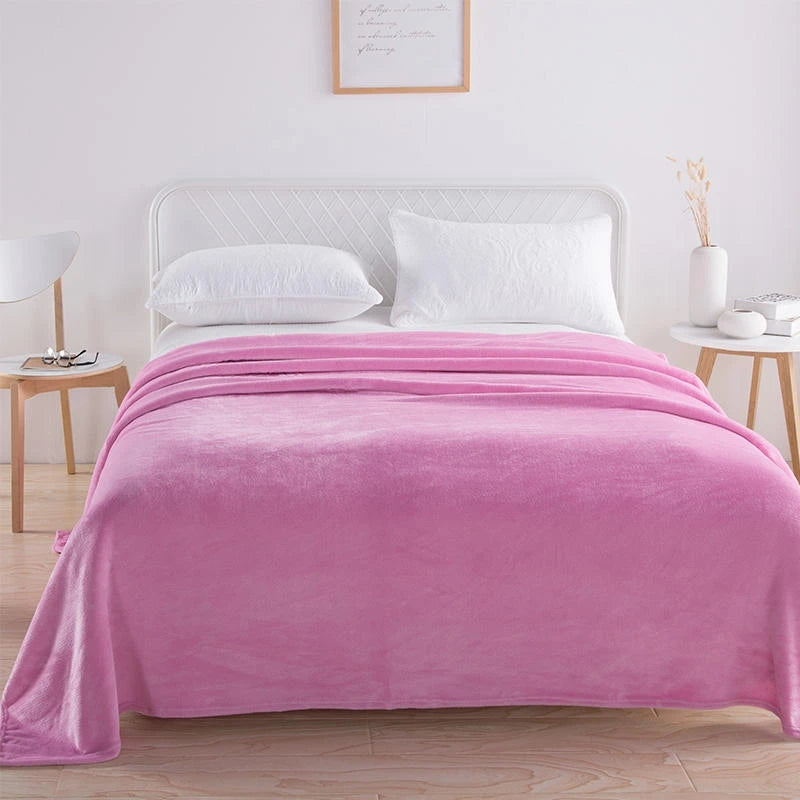 Pink plush blanket covering a white bed in a bright bedroom