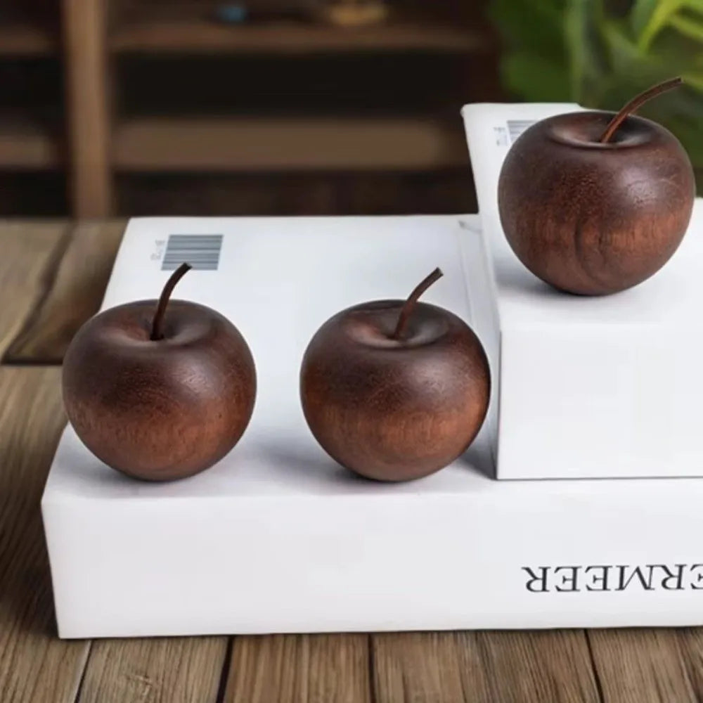 Three wooden apple-shaped diffusers on a white box with a blurred background