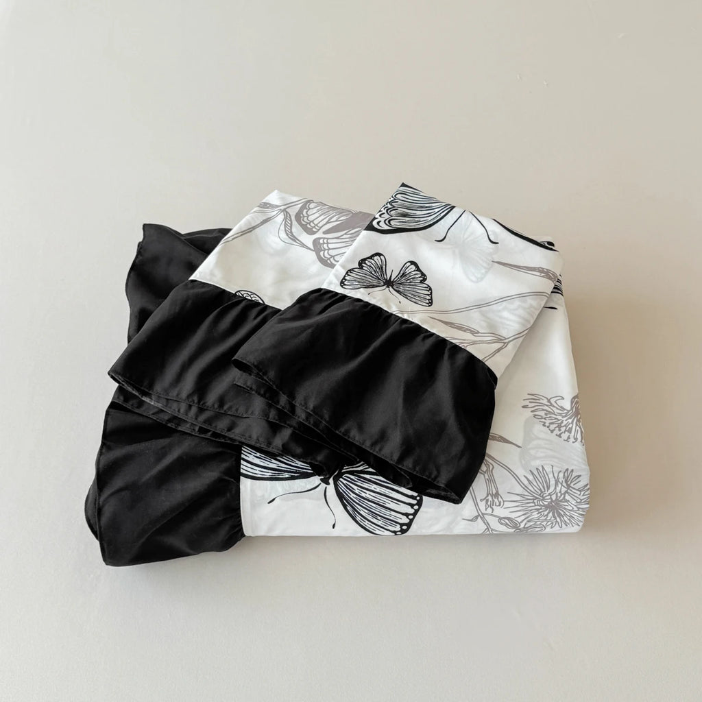A neatly folded Monarch Butterfly bedding set, showcasing the contrast between the intricate butterfly pattern and the solid black ruffle.