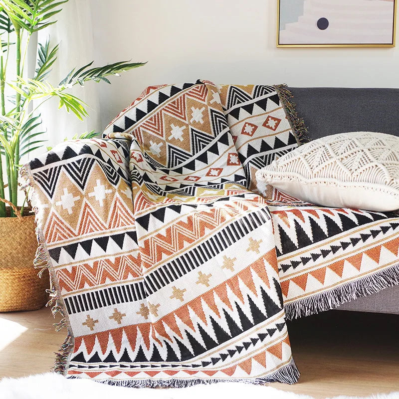 Black and tan tribal-inspired woven blanket with intricate orange diamond motifs.