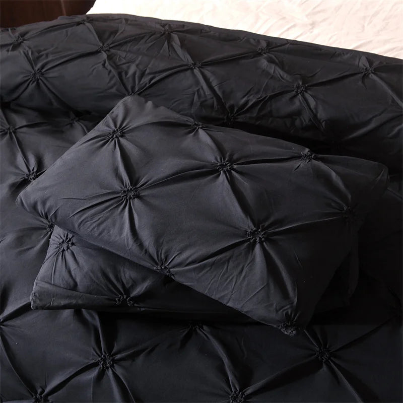Black pintuck duvet set with matching pillowcases dressed on a double bed in a warm contemporary bedroom