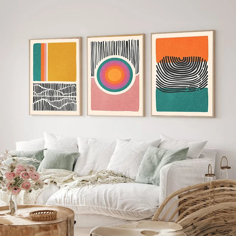 Three abstract canvas prints in mustard, orange, teal and pink with bold line art details