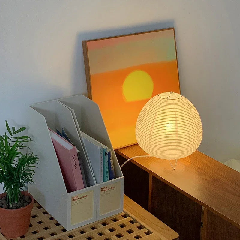 Japanese Lamp on a wooden surface with a plant and books in the background