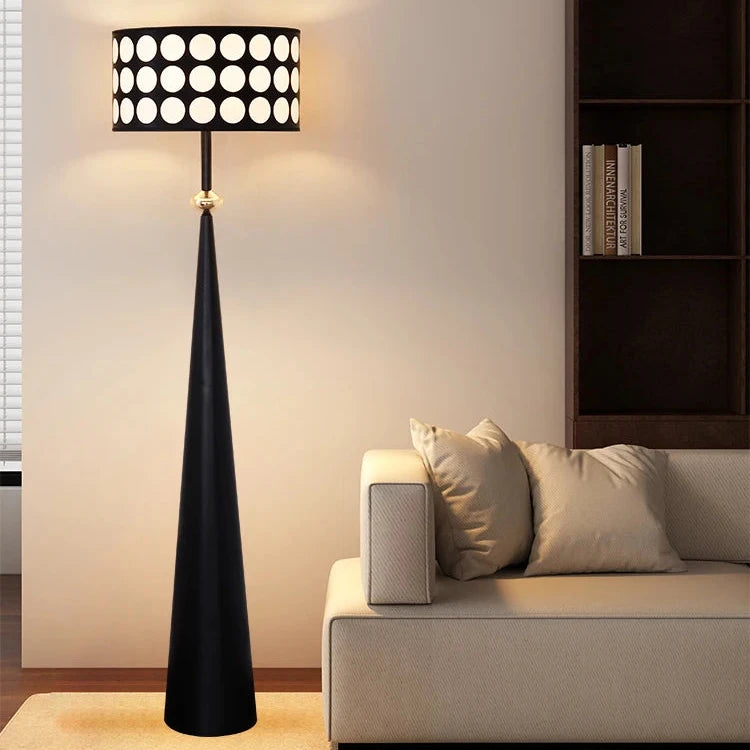 Black floor lamp with white polka dot shade in a living room setting.