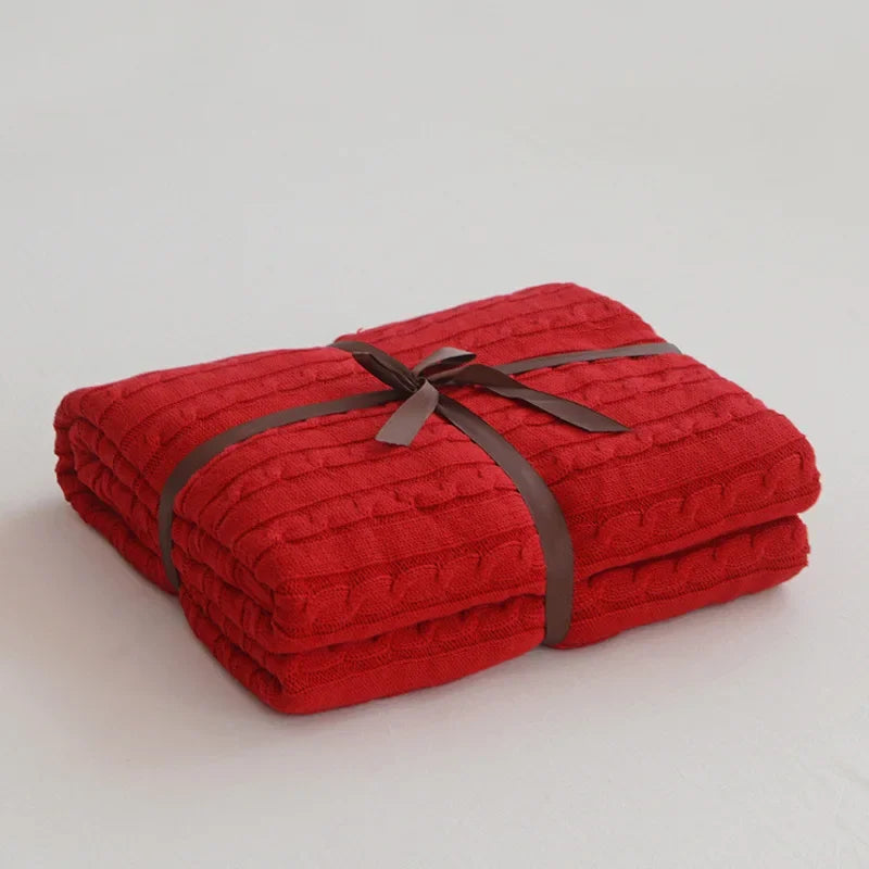 Folded red blanket tied with a brown ribbon on a light gray background