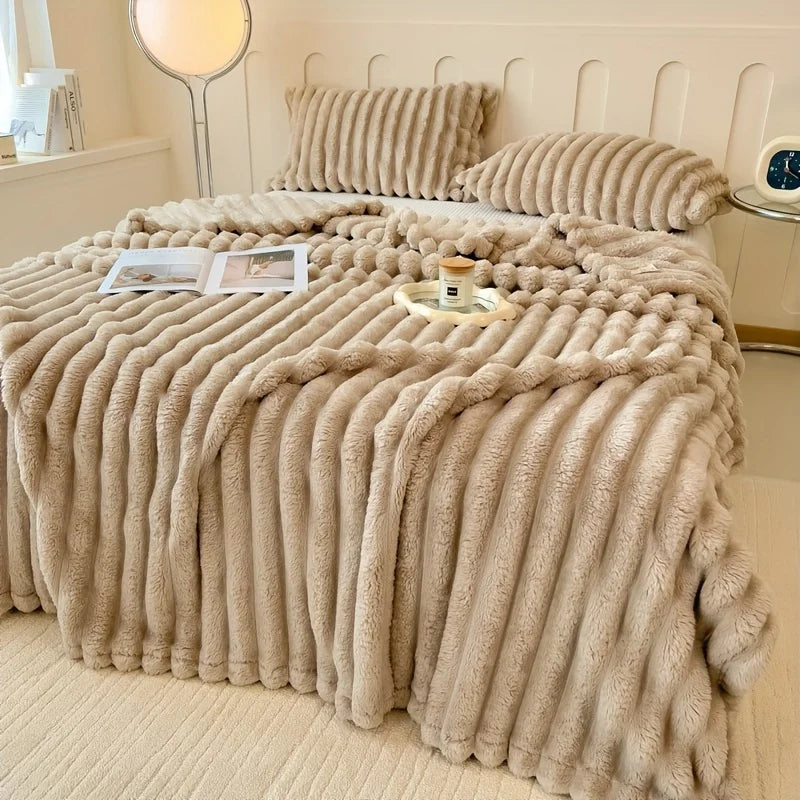 Beige fluffy blanket draped over a bed in a bedroom setting.
