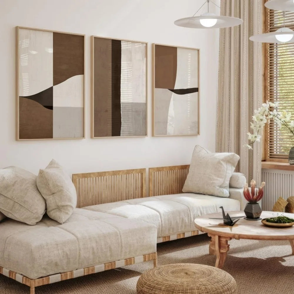 Neutral living room with three framed abstract canvas prints in warm brown, cream, and beige tones above a wooden daybed