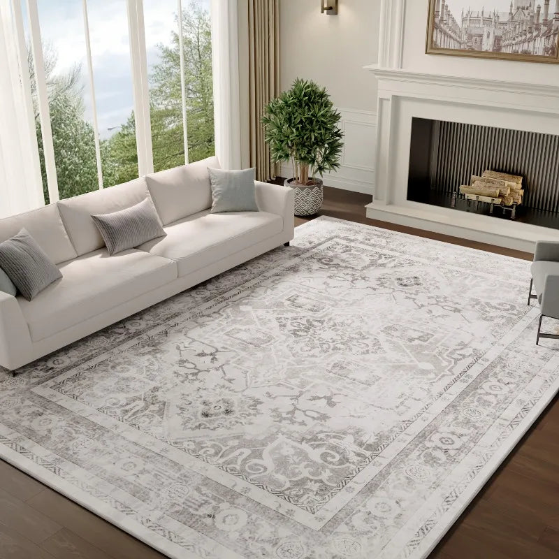 Large silver grey Persian-style medallion rug laid in a bright living room with a white sofa and a fireplace