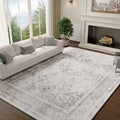 Large silver grey Persian-style medallion rug laid in a bright living room with a white sofa and a fireplace