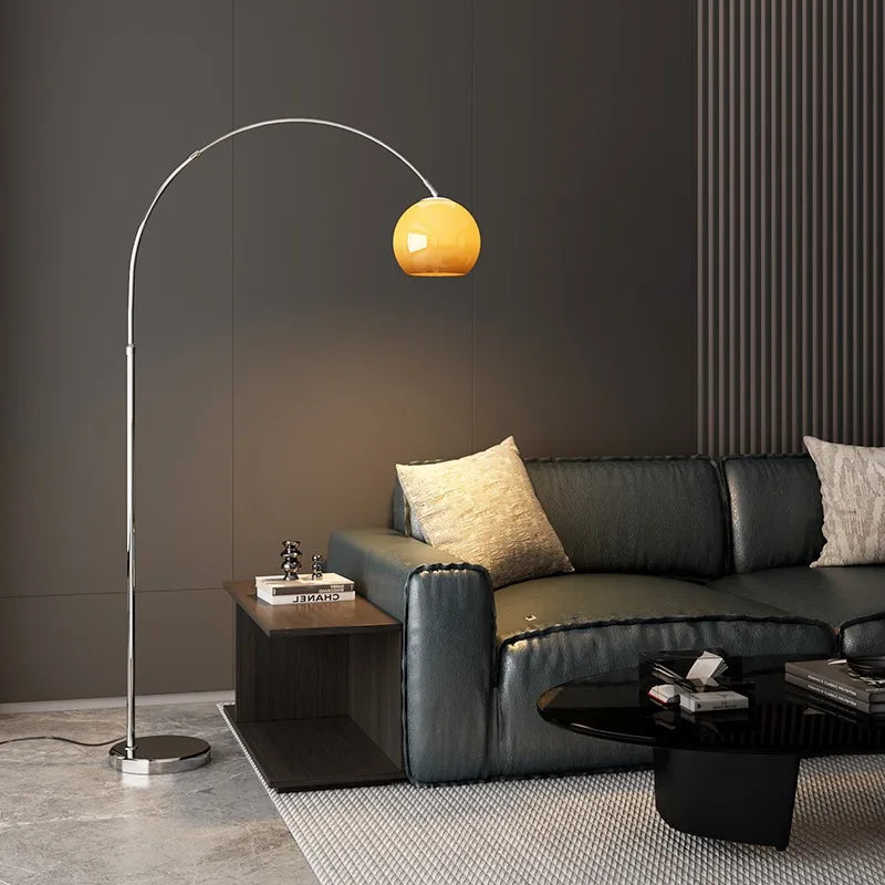 Mushroom-shaped Bauhaus floor lamp with arched metal frame and amber glass shade beside a black leather sofa