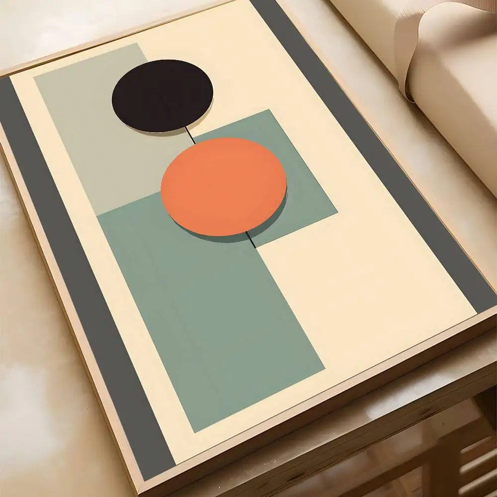 Abstract geometric canvas print featuring black and orange circles with a sage green rectangular block on a cream background, in a wood frame.