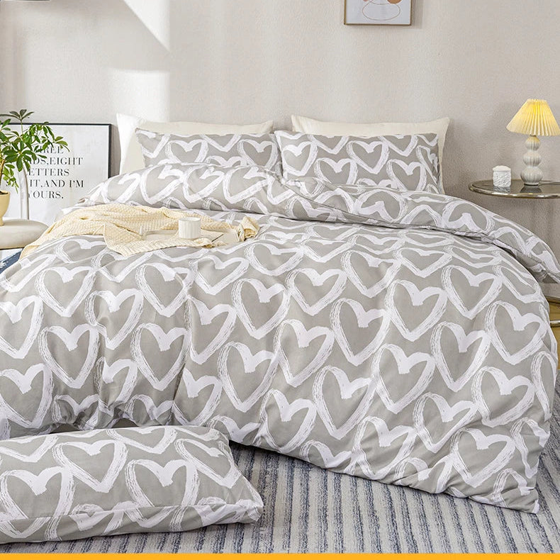 Gray and white heart-patterned comforter set on a bed in a bedroom.