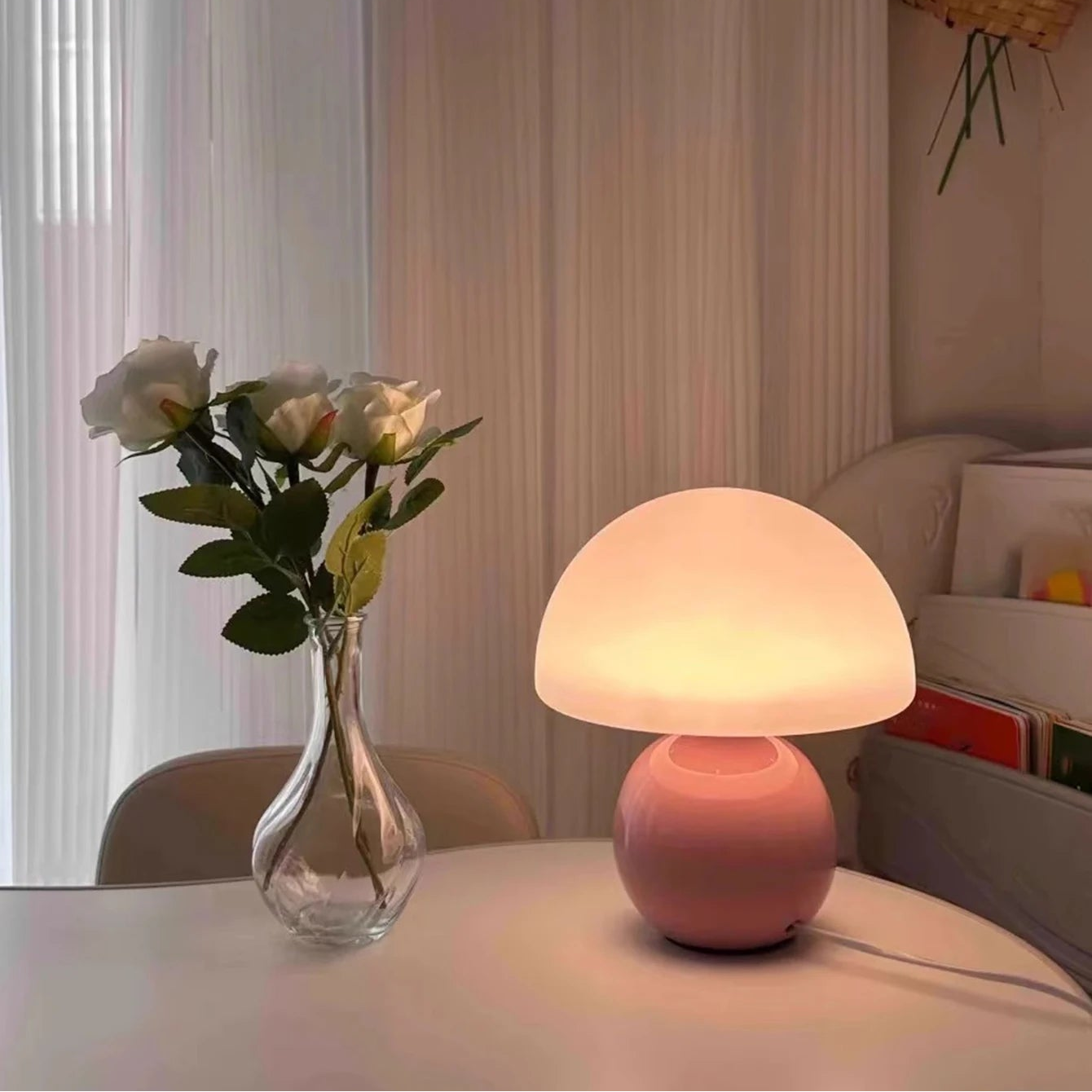 Pink table lamp on a surface with a vase of flowers and a blurred background