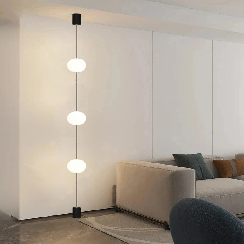 Contemporary lounge space with 3-head floor-to-ceiling LED globe light next to a rounded white armchair