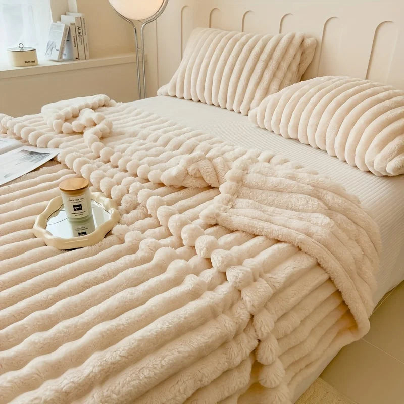 Beige textured blanket draped over a bed with pillows and a tray in a bedroom setting.