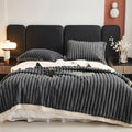 A charcoal grey textured comforter on a bed in a bedroom setting