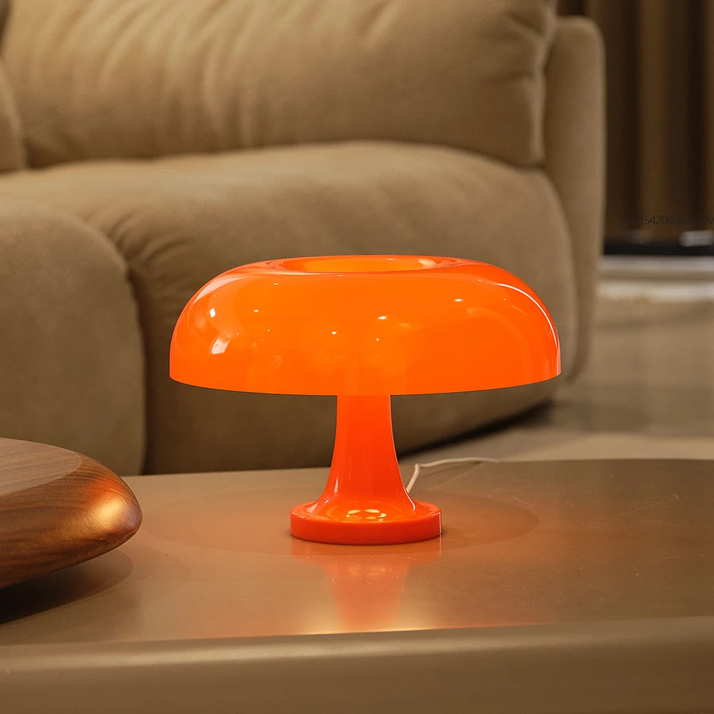 Orange table lamp on a wooden surface with a blurred beige sofa in the background