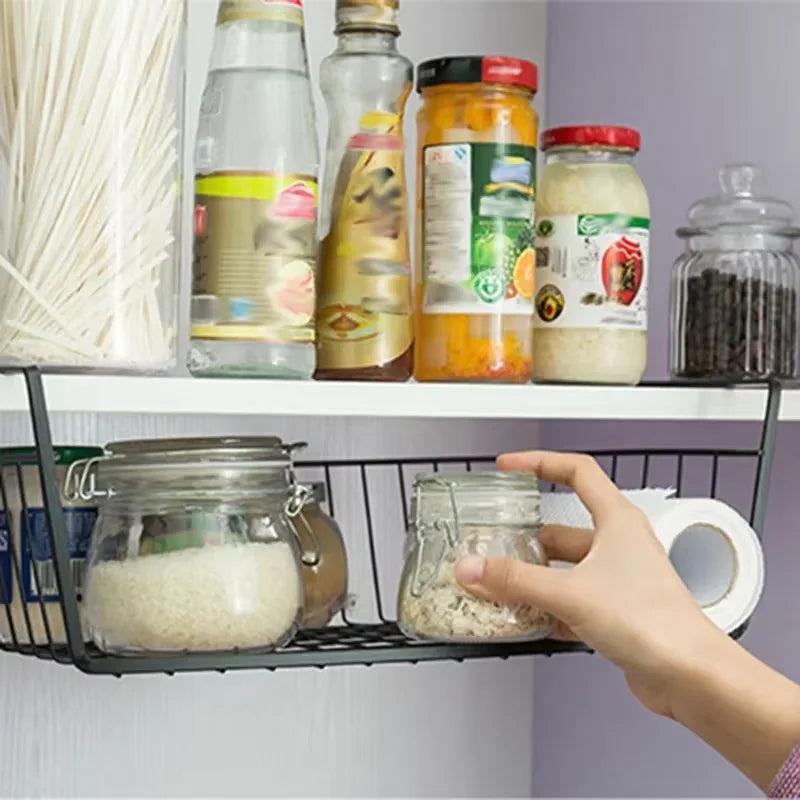 Hand reaching for a jar on a kitchen shelf with various food items.