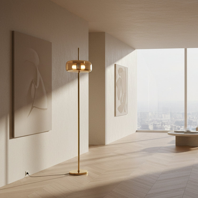 Minimalist gold floor lamp with amber glass shade lit in a warm glow.