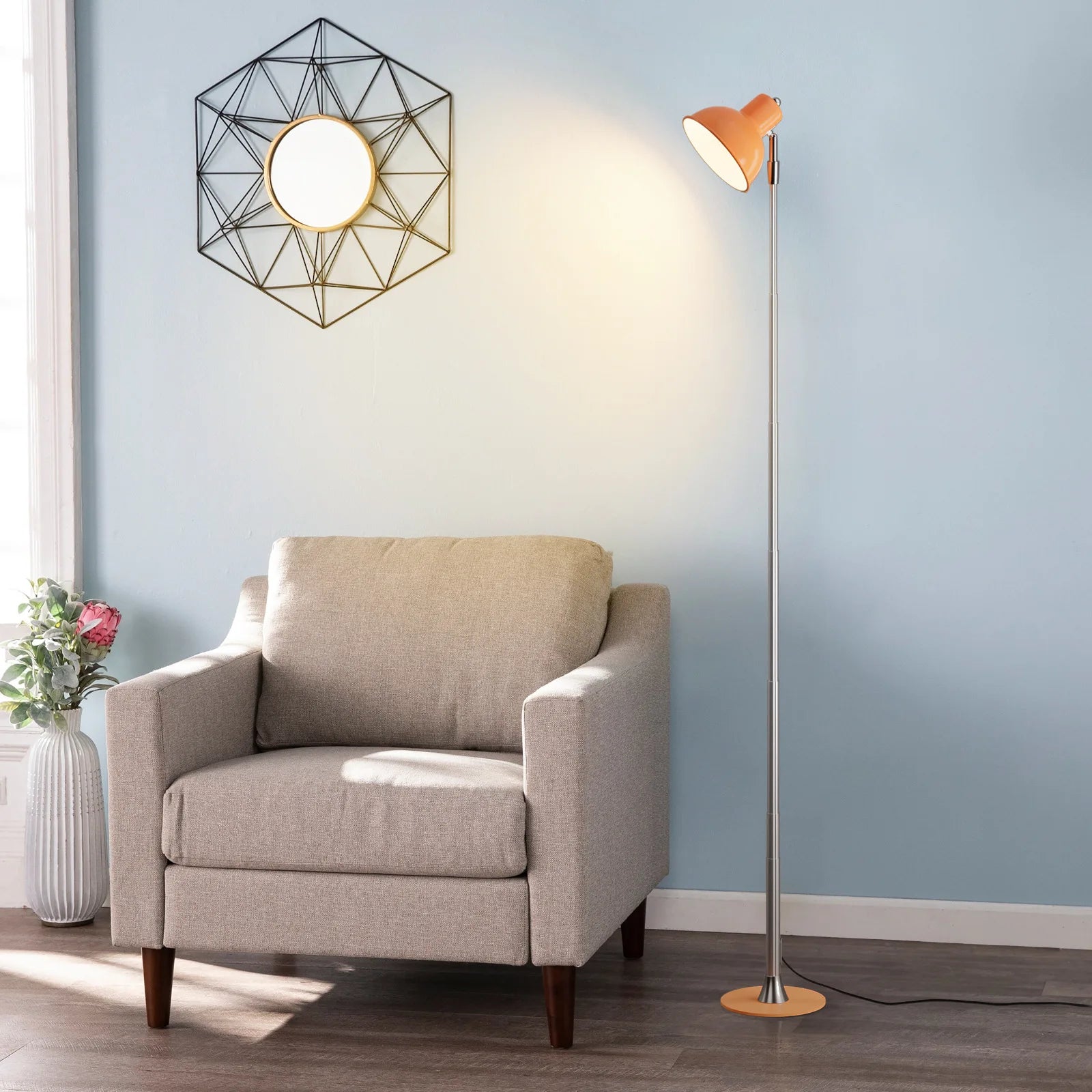 Beige armchair in a room with a geometric wall light fixture and a standing lamp.