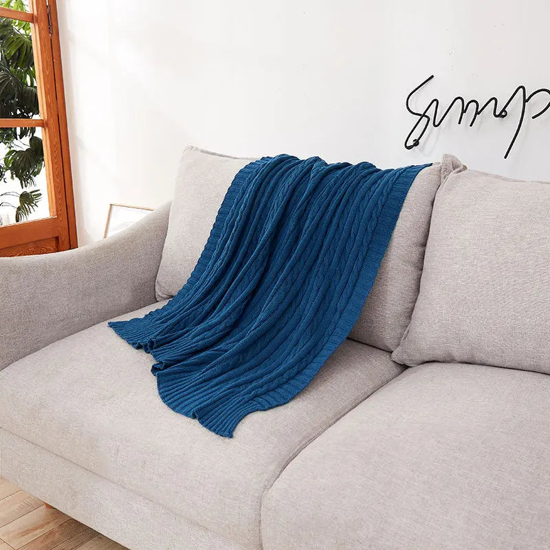 Blue blanket draped over a gray sofa with a blurred indoor background