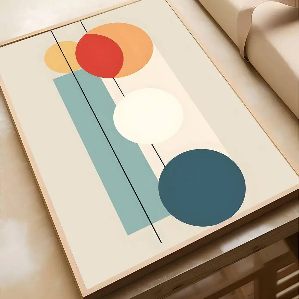 Abstract canvas print with overlapping yellow, red, orange, and teal circles balanced on a soft teal rectangular block on a cream background, in a wood frame.