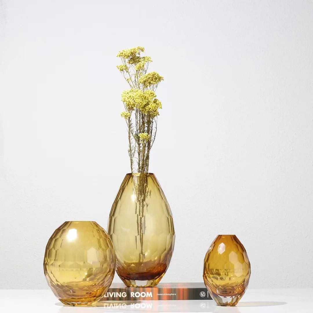 Three amber-coloured vases on a white surface with a light gray background