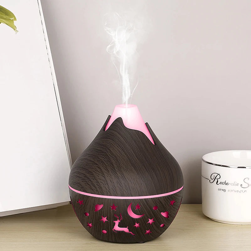 Black and pink essential oil diffuser on a wooden surface with a blurred background