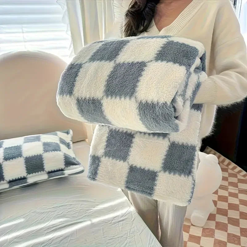 Person holding a checkered blue & white blanket with a blurred indoor background