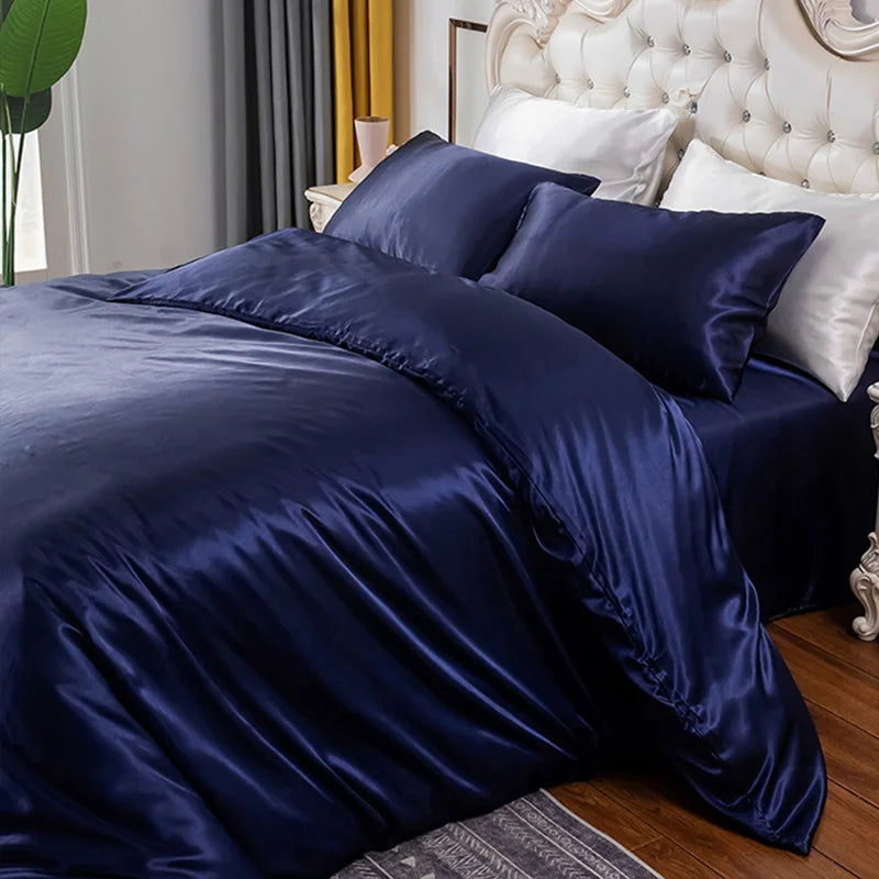 Navy blue satin bedding set on a bed with white pillows and headboard.