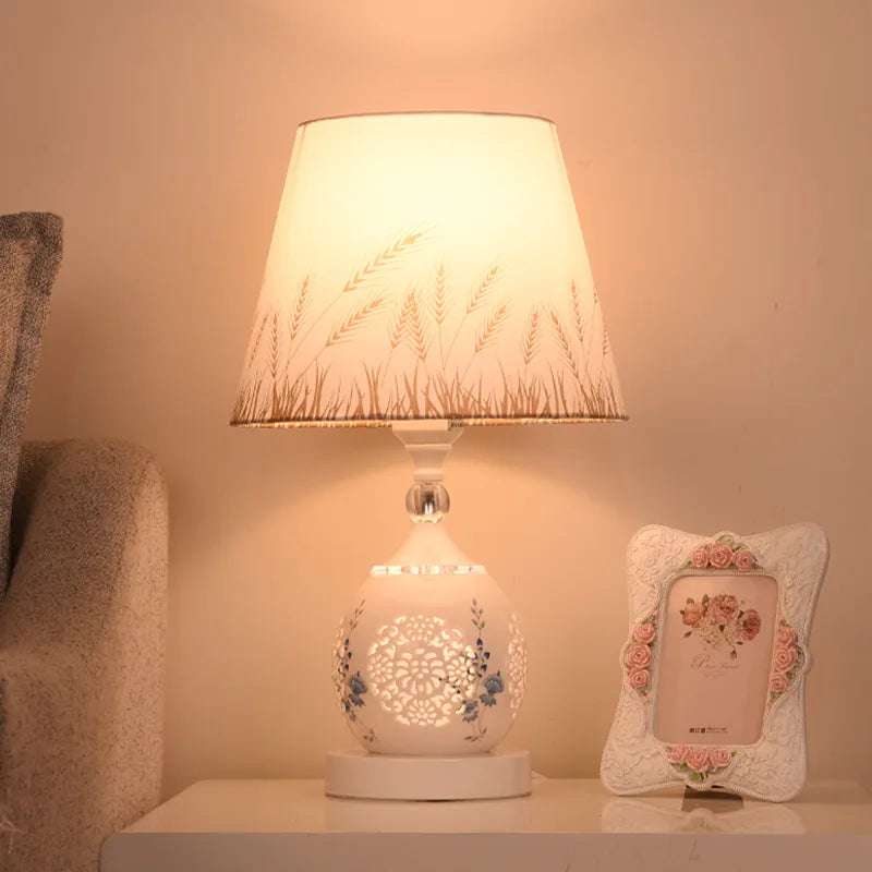 White floral cut-out base lamp with golden wheat pattern lampshade casting a warm glow.