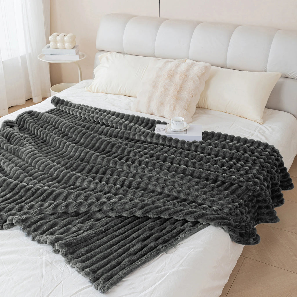 Gray textured blanket draped over a bed in a bedroom setting
