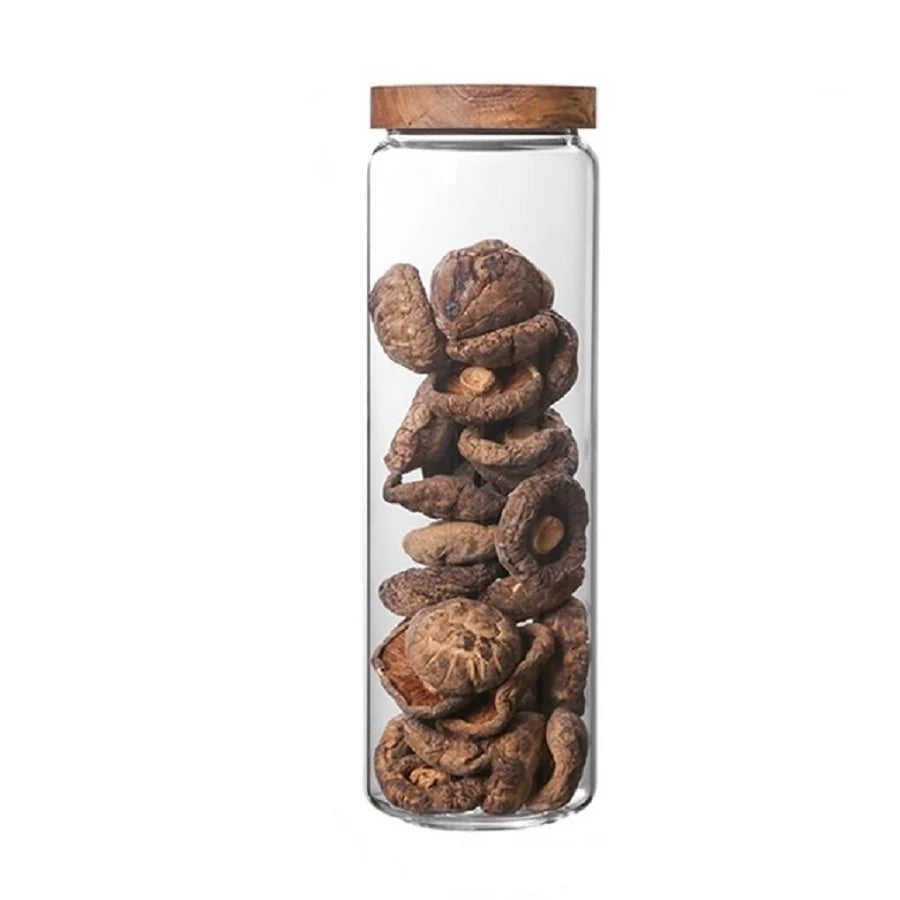 Glass jar with wooden lid containing dried mushrooms on a white background
