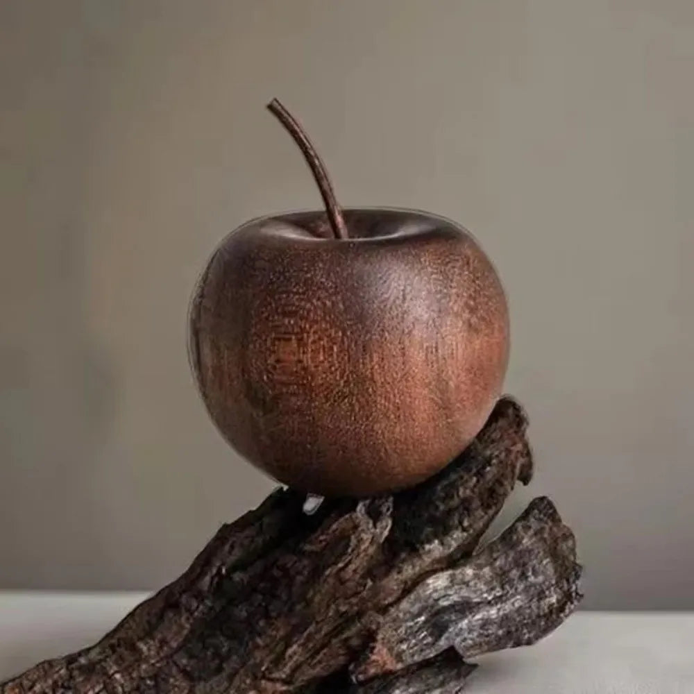 An apple-shaped diffuser on a wooden branch against a plain background