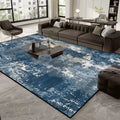 Living room with a blue abstract rug, gray sofa, and modern decor.