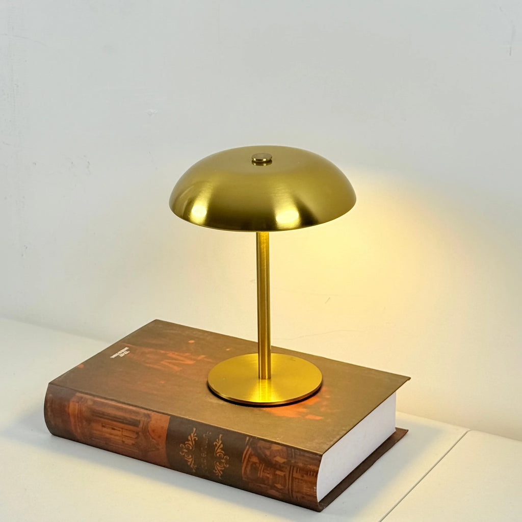 Gold mushroom table lamp on a book with a soft white background
