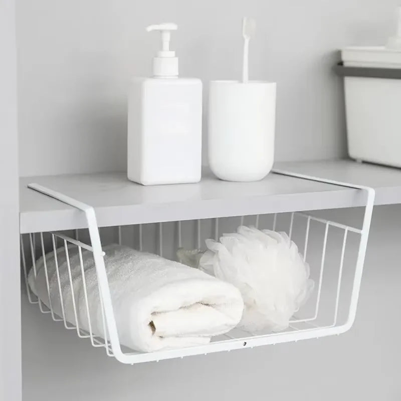 White wire basket under a shelf with folded towels and bathroom items on a light gray background