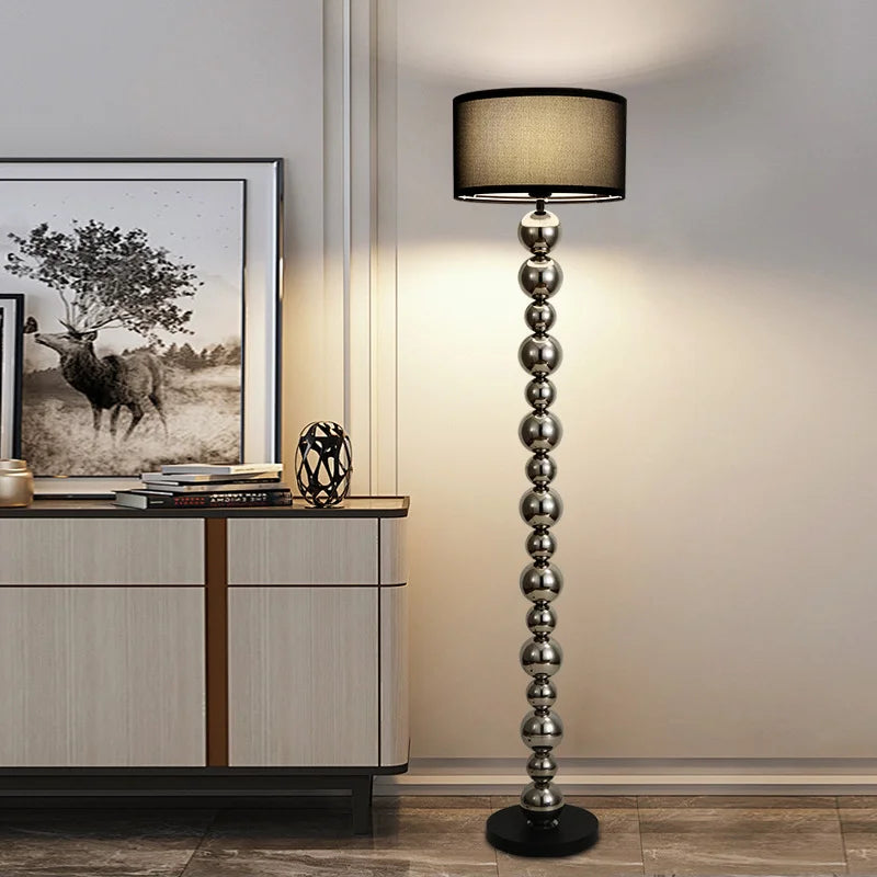 Stainless steel sphere floor lamp with black fabric shade beside the sideboard