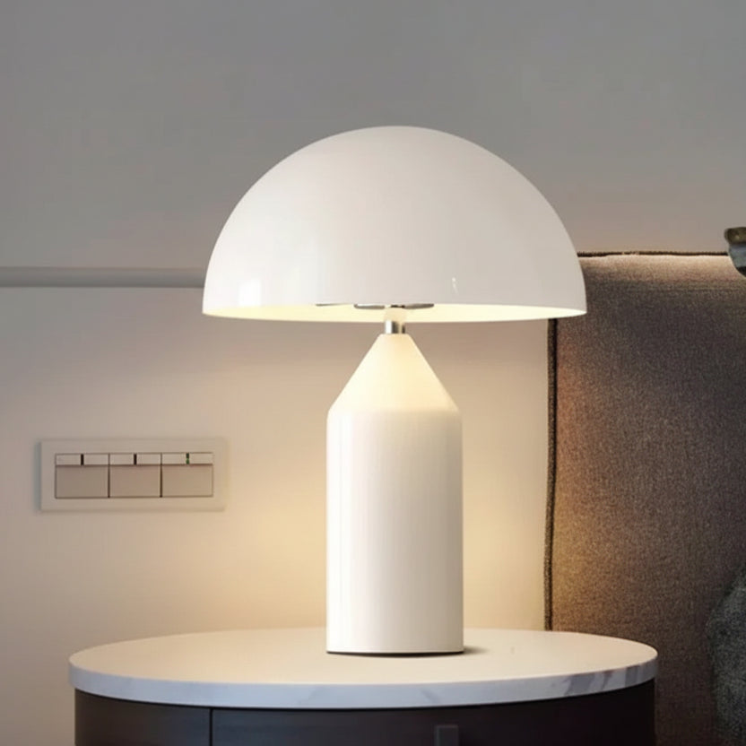 White table lamp on a side table next to a sofa with cushions.