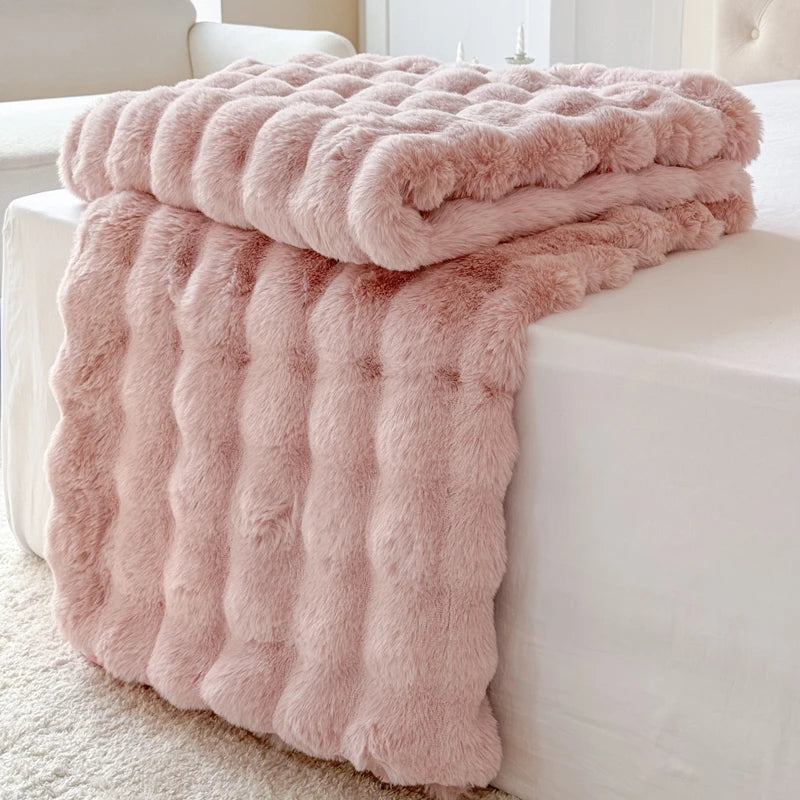 Pink fluffy blanket draped over a white sofa