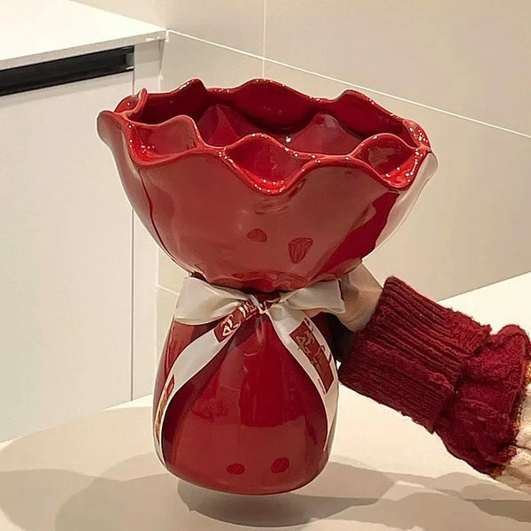 Red ceramic vase with a white ribbon and red gloves on a light background
