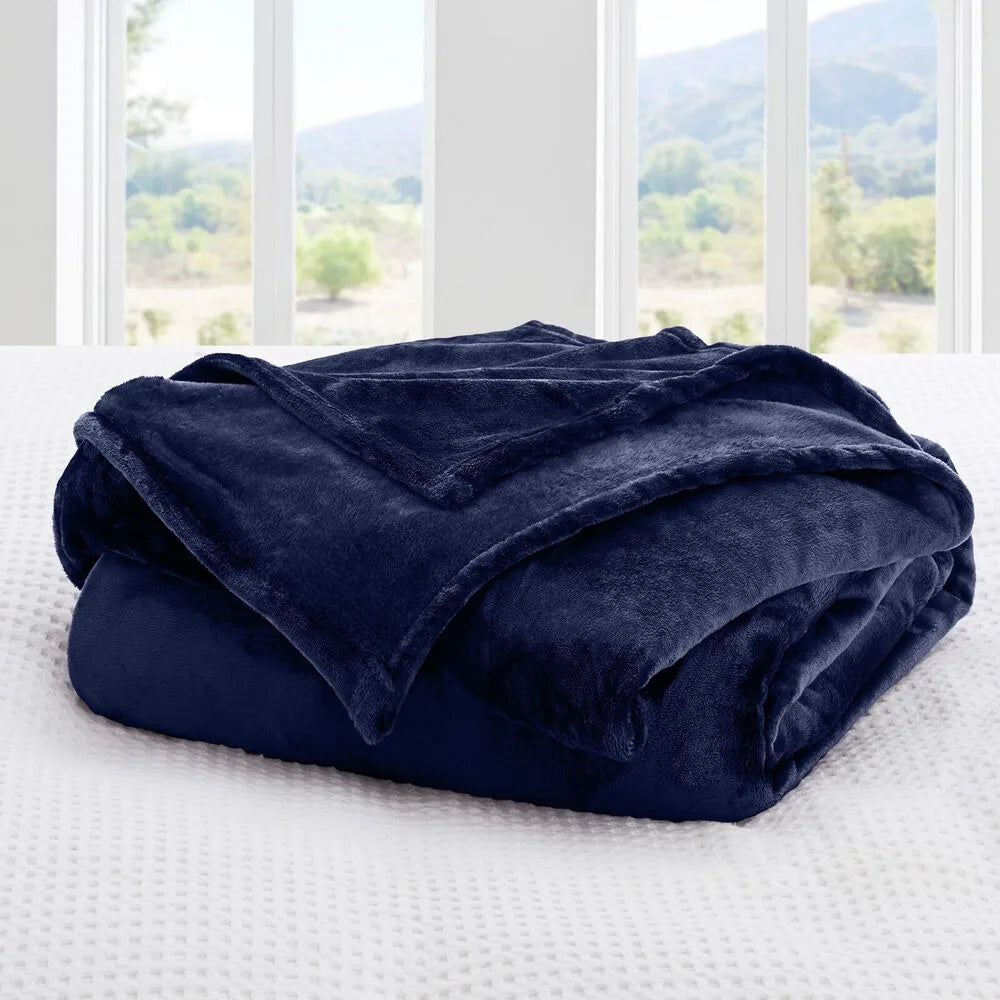 Navy blue blanket on a bed with a window view of trees and mountains.